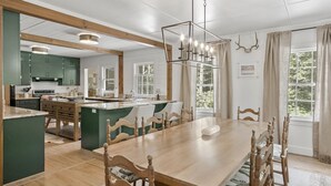 A spacious kitchen with a central island, wooden dining table, and chairs. - 15% Off! Three Generations Built This House. Now It's Yours For the Week | The Bird Coop (Highlands)