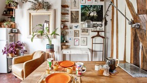 A dining area with a wooden table set for four, surrounded by a rustic interior with exposed beams and a variety of wall decorations. - Studio Listelli - Welkeys (Paris)