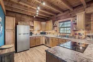 A kitchen with wooden cabinets, a stainless steel refrigerator, a microwave, and a granite countertop.