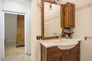 A bathroom with a wooden vanity, a white sink, and a mirror.