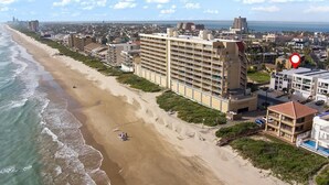Un hotel costero con varios pisos, ubicación frente a la playa y vista al océano.
