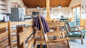 A rustic kitchen with wooden cabinets, a refrigerator, and a dining area with wooden chairs. - 3 Bedroom, 3.5 bath home in The Galena Territory (Galena)