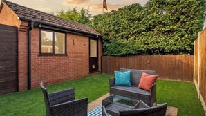 Un jardin avec un ensemble de mobilier de patio, une maison en briques et une clôture en bois.