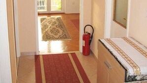 A hallway with a red carpet, a fire extinguisher, and a clock on the wall. - waterfront apartment family friendly, ground level (Dubrovnik)