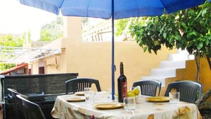 An outdoor dining area with a table set for two, a bottle of wine, and a bowl of lemons. - waterfront apartment family friendly, ground level (Dubrovnik)