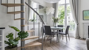 A modern interior with a staircase, dining area, and large windows.