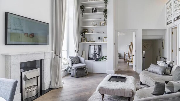A modern living room with a fireplace, a sofa set, a coffee table, and a bookshelf with decorative items.