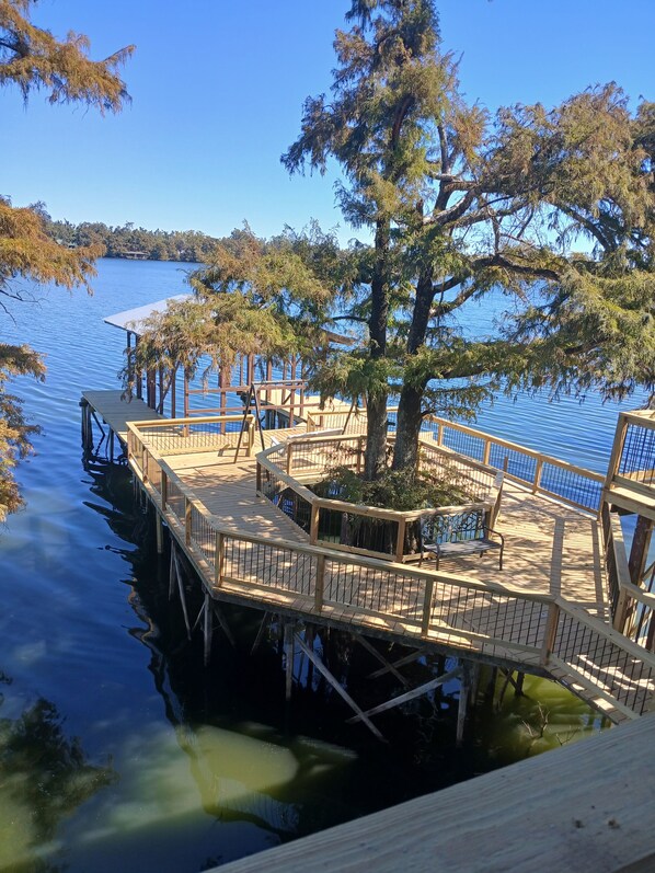 A wooden dock extending into a calm lake, surrounded by trees and a clear sky.