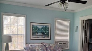 A bedroom with a bed, a ceiling fan, and two windows with blinds. - The Lily Pad (Lake Providence)