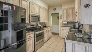 A kitchen with light wooden cabinets, a stainless steel refrigerator, a microwave, an oven, and a sink. - The Lily Pad (Lake Providence)