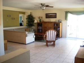 Relax in this inviting living room with a sofa, armchair, and book-filled cabinet.