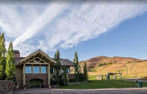 Situated in a natural setting, the Dollar Mountain Lodge features a log cabin-style exterior with a stone archway and a wooden front door.