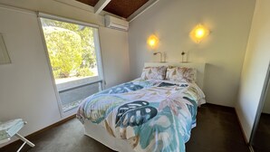 A bedroom with a bed, a window, a bedside table, and a wall-mounted light fixture. - Riverport Retreat - Pet Friendly, close to the river, free Wifi + linen included (Goolwa South)