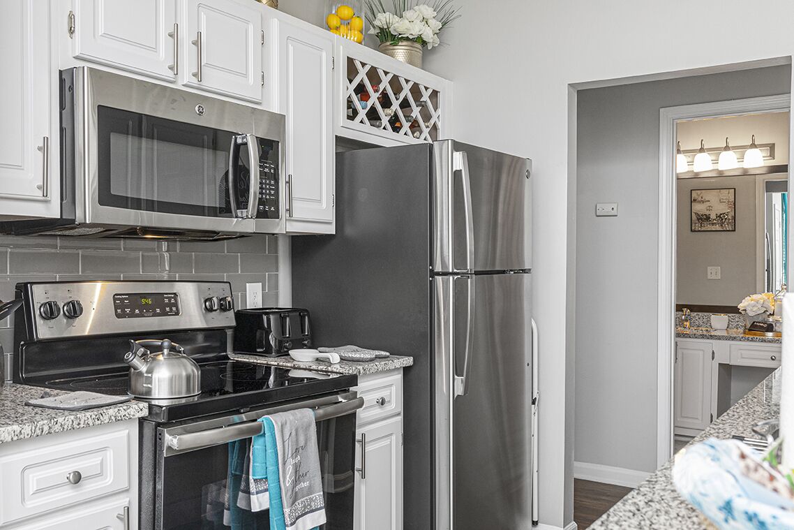 A modern kitchen with stainless steel appliances, white cabinetry, and granite countertops.