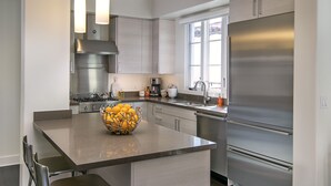 A modern kitchen with a central island, stainless steel appliances, and a dark wood floor. - Luxury Top Floor Condo in Heart of Downtown Santa Barbara  (Santa Barbara)