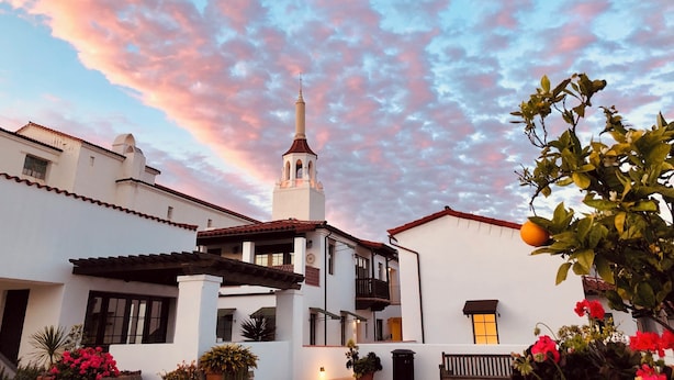 A white building with a bell tower, surrounded by greenery and flowering plants. - Luxury Top Floor Condo in Heart of Downtown Santa Barbara  (Santa Barbara)