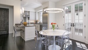 A modern kitchen with a central island, clear chairs, and a round table with a vase of flowers. - Luxury Top Floor Condo in Heart of Downtown Santa Barbara  (Santa Barbara)