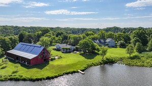 A large property with a red barn, multiple houses, and a lake.