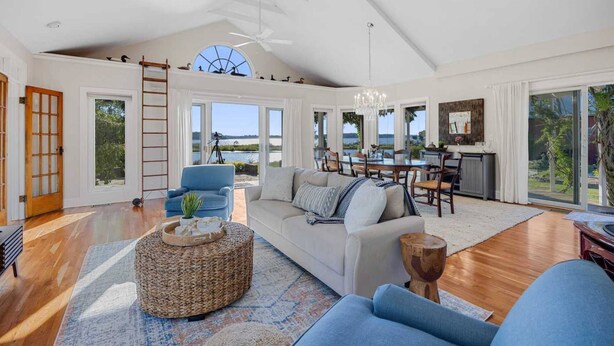 A spacious living room with a large sofa, a dining area, and a view of the outdoors.