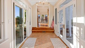 A hallway with glass doors, a chandelier, and a view of the backyard.