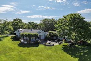 A large house with a well-maintained lawn and a patio area. - Serene Sunsets at Historic Waterfront Home (Annapolis)