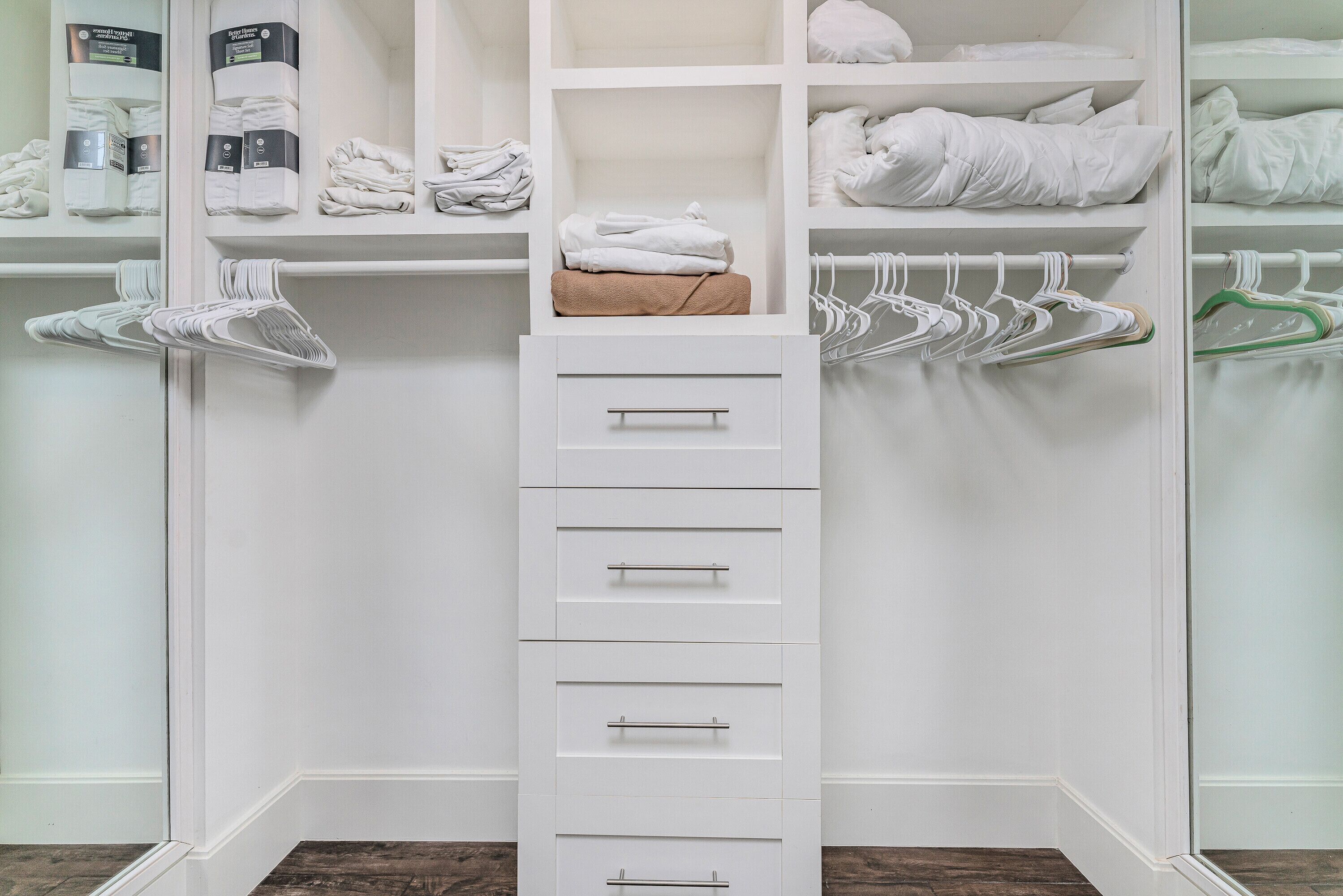 Un placard blanc doté de nombreuses étagères, de tiroirs et d’un espace pour suspendre les vêtements.
