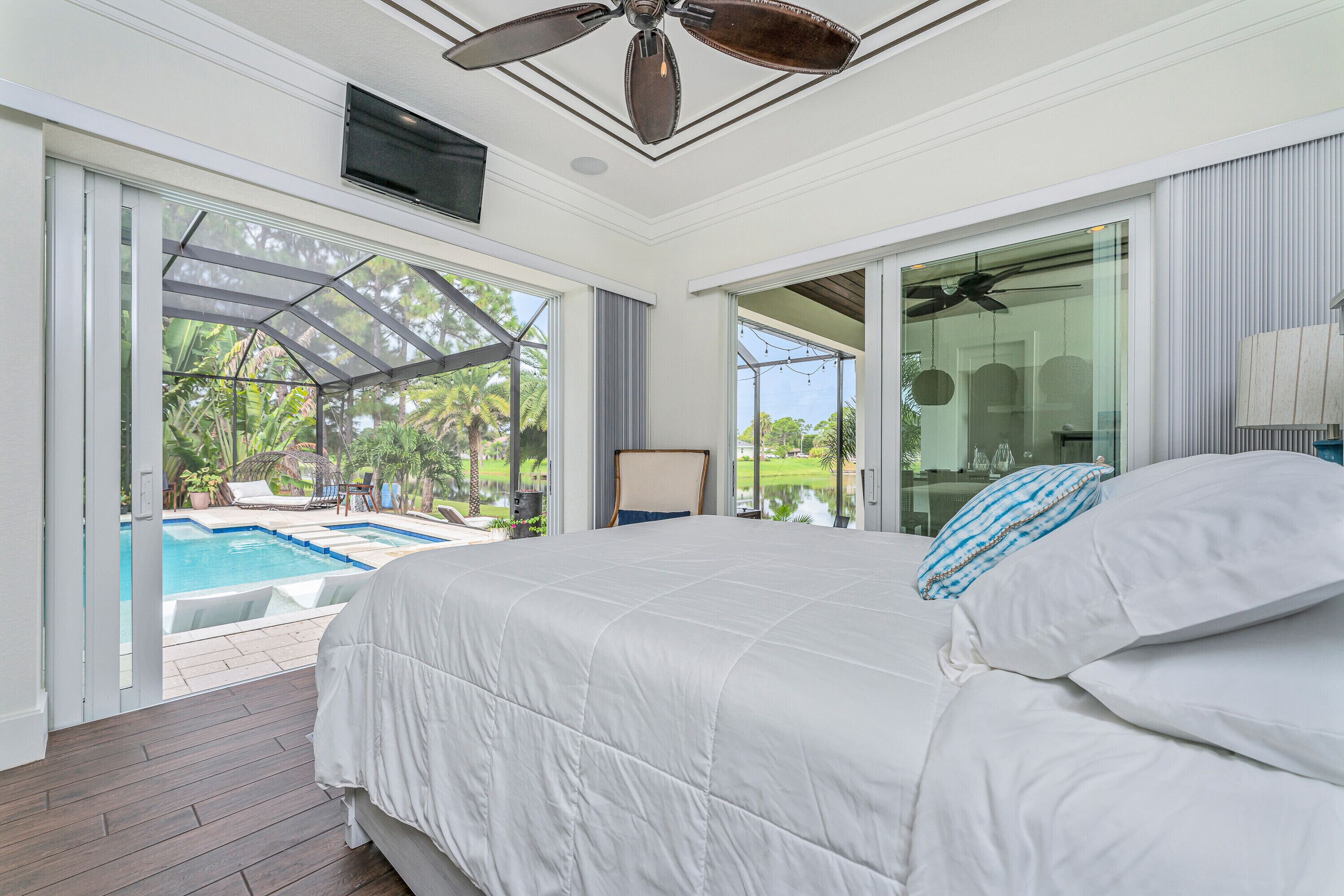 Ein Schlafzimmer mit einem großen Bett, einem Deckenventilator und Blick auf einen Swimmingpool.