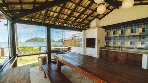 Una cocina con vista al mar, una mesa de madera y un banco.