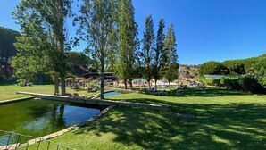 Un espace extérieur ensoleillé avec une piscine, des chaises longues et une pelouse verdoyante.