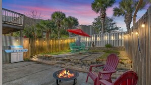 A backyard with a fire pit, outdoor seating, and a wooden fence.