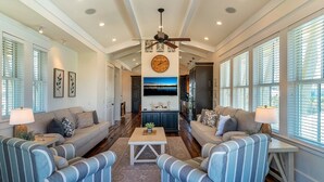 A spacious living room with a high ceiling, a central fireplace, and a large clock on the wall. - Breathtaking Home w/Private Pool, Walk 2 Beach w/Beach Wagon, Pools, Hot Tub, Tennis - Destin Pointe (Destin)