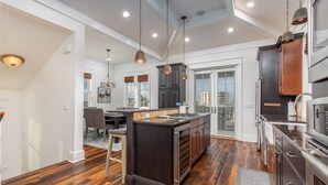 A spacious kitchen with dark wooden cabinets, a central island, and pendant lighting. - Breathtaking Home w/Private Pool, Walk 2 Beach w/Beach Wagon, Pools, Hot Tub, Tennis - Destin Pointe (Destin)