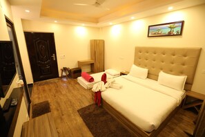 A hotel room with a large bed, a wooden floor, a TV, and a painting on the wall. - Avenue 18 Resort (Yamkeshwar)