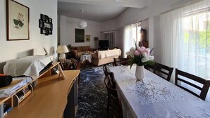 Ein geräumiges Wohnzimmer mit Esstisch, einer Couch und einem Fernseher.