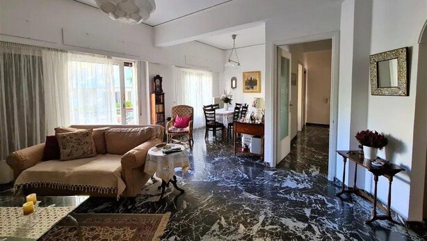 Ein geräumiges Wohnzimmer mit einer großen Couch, einem Essbereich mit Stühlen und einem Marmorboden.