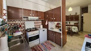 Eine kleine Küche mit Gasherd, Spüle und Mikrowelle. Es gibt einen Essbereich mit Tisch und Stühlen.
