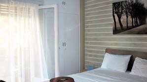 Ein Schlafzimmer mit einem Bett, einer Gitarre, einer Tür und einem Gemälde an der Wand.