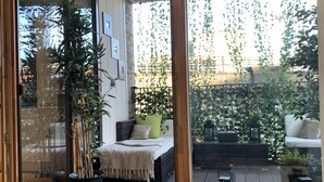 A modern interior with a sliding glass door leading to a balcony with plants and outdoor furniture. - Notting Hill 2-bed Apt With Balcony, 1 min to Tube (London)