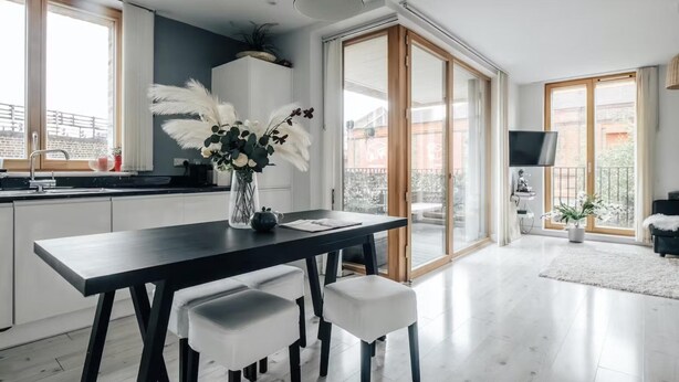 A modern kitchen with a black dining table, white chairs, and a vase with flowers. - Notting Hill 2-bed Apt With Balcony, 1 min to Tube (London)