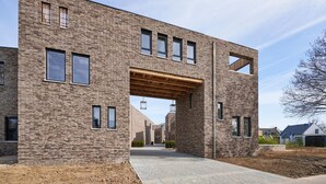 A modern building with a brick facade, large windows, and a covered walkway. - Maastricht Wellness Loft (Maastricht)