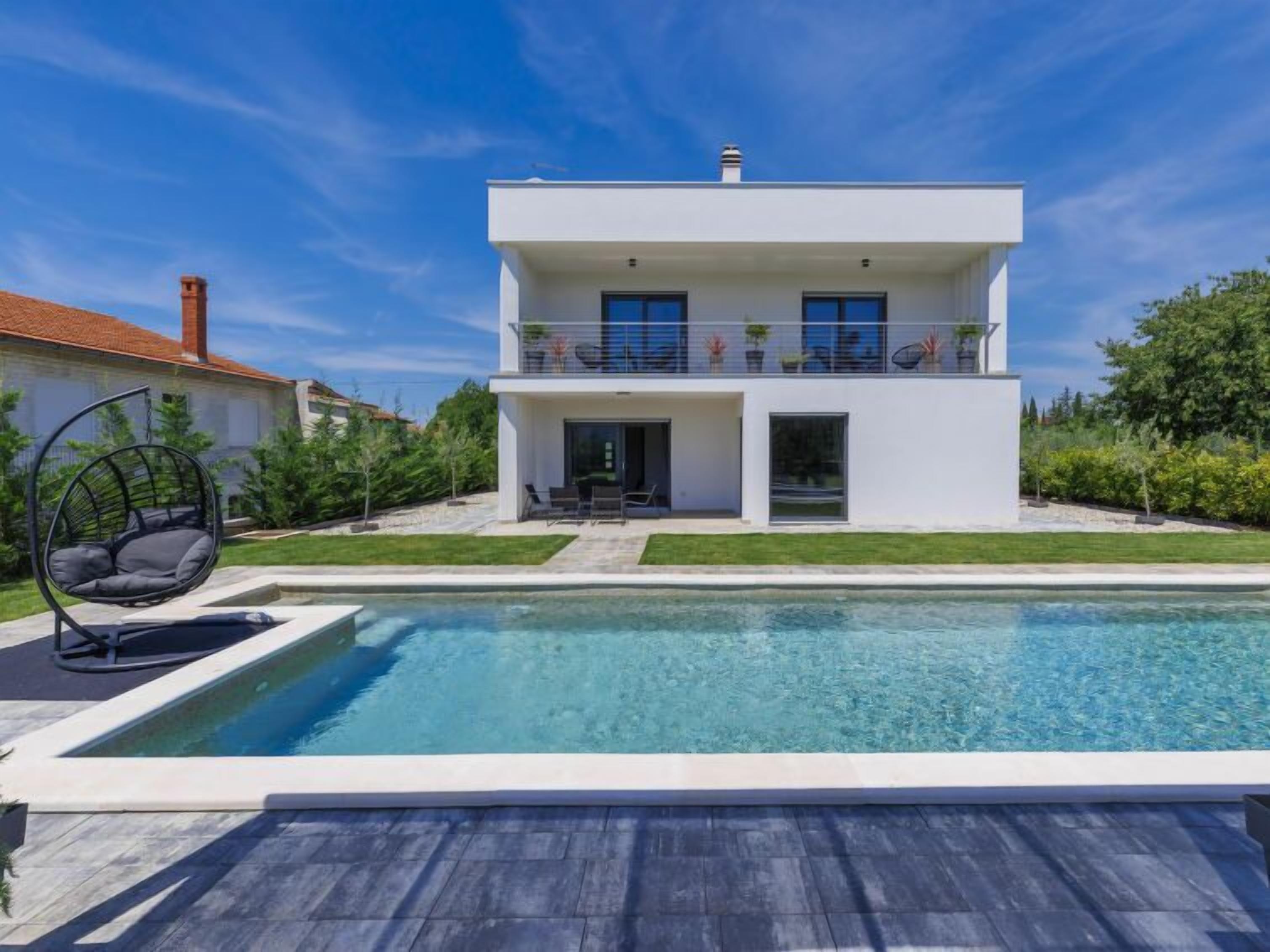 Una casa moderna de dos pisos con una piscina al frente.