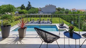 A rooftop terrace with a pool, lounge chairs, and potted plants.