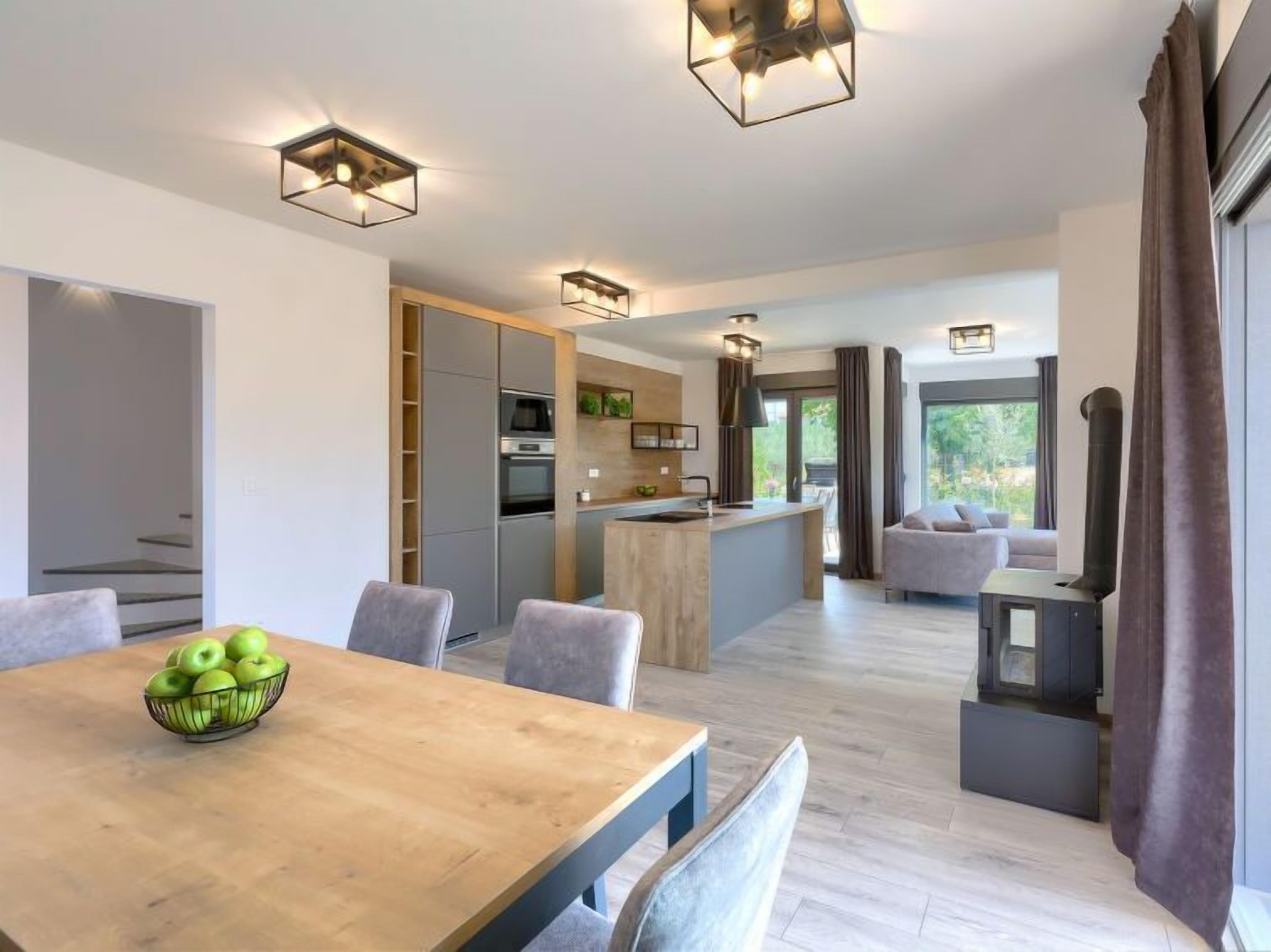 A modern kitchen with built-in appliances, a dining area with a wooden table and chairs, and a cozy seating area with a sofa and a fireplace.