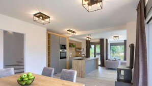 A modern kitchen with built-in appliances, a dining area with a wooden table and chairs, and a cozy seating area with a sofa and a fireplace.