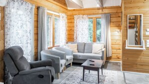 L’intérieur d’un chalet confortable, avec un canapé, des fauteuils et une petite table.