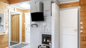 Un intérieur moderne avec une cheminée, un téléviseur fixé au mur et une porte donnant sur une autre pièce.