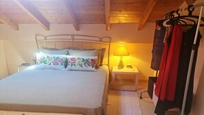 Un dormitorio con una cama, una mesita de noche con lámpara y un perchero.