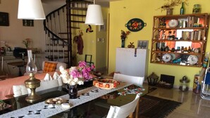 Un comedor con mesa de vidrio, sillas blancas, mantel individual de encaje y una araña.