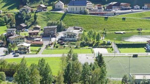 A small village with a mix of residential and commercial buildings, a church, and a sports field. - Apartment Gams by Interhome (See)