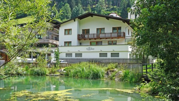 A hotel with a pond, lily pads, and surrounding greenery. - Apartment Gams by Interhome (See)